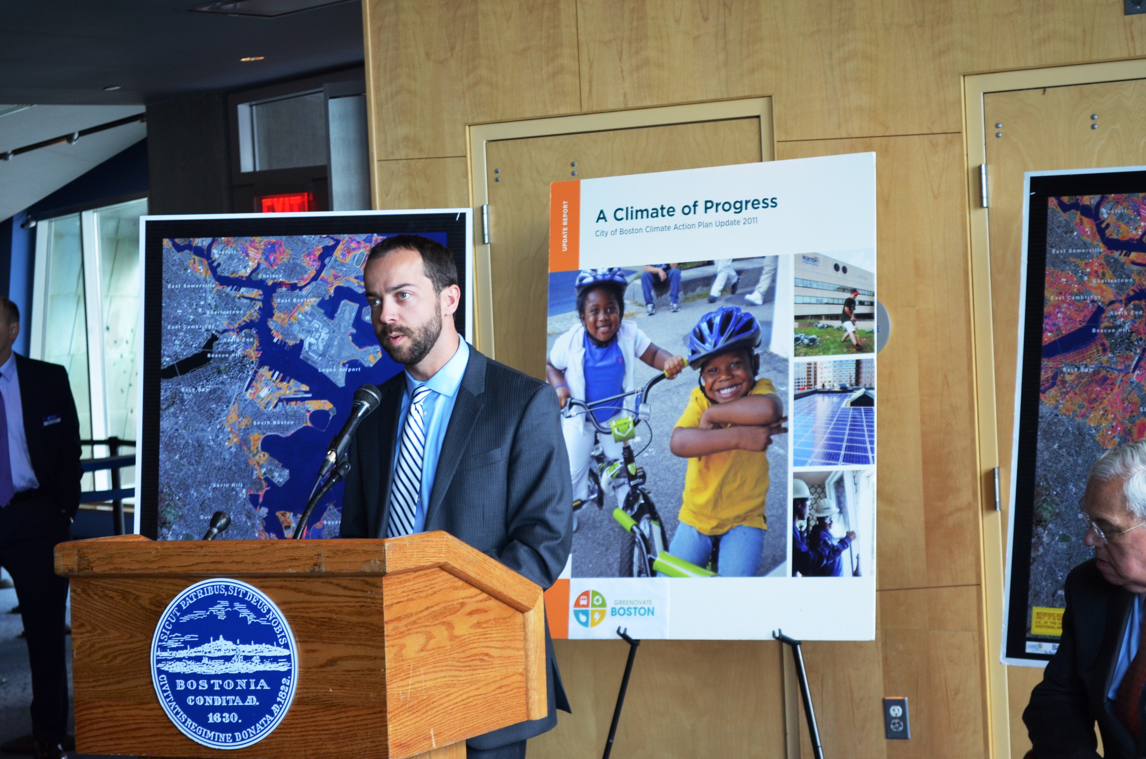 Brian Swett standing at a podium with posters in background