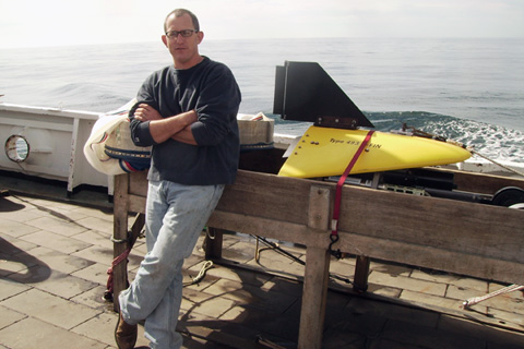 John Hare standing on a pier with ocean in background