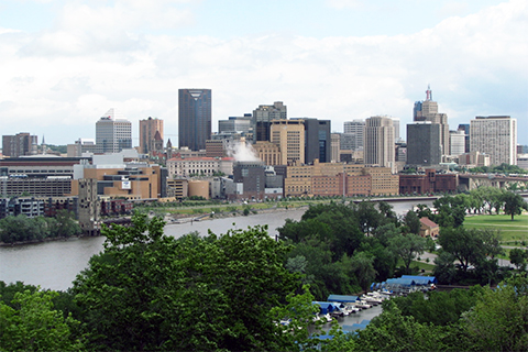 Trees and greenspace in foreground, river and urban center background
