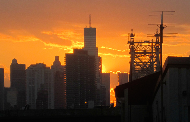 Sun setting behind skyscrapers