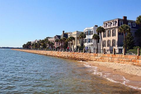 View from water of a sea wall and historic homes behind it