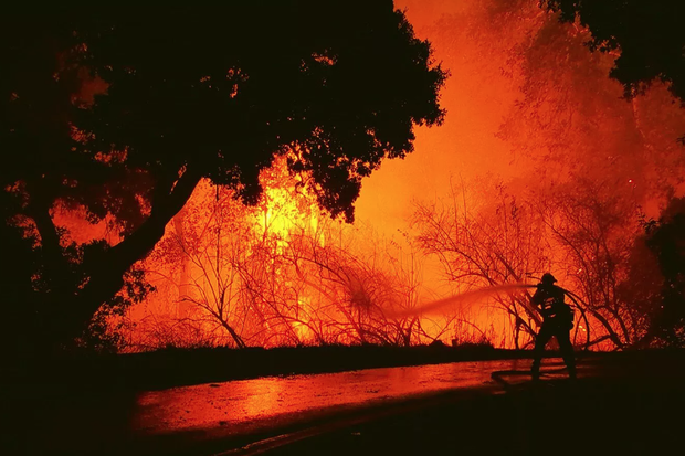 Firefighter aims hose at wildfire