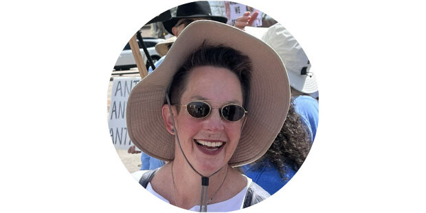 photo of a smiling woman in the sun wearing a hat and sunglasses
