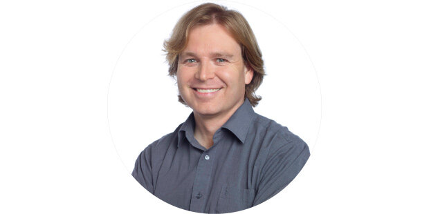photo of a man, smiling and wearing a grey shirt